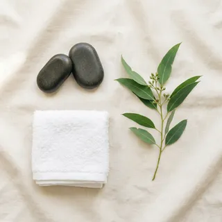 Warm massage stones and a folded towel with eucalyptus