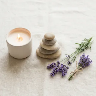 Lit candle, balancing stones and lavender sprigs